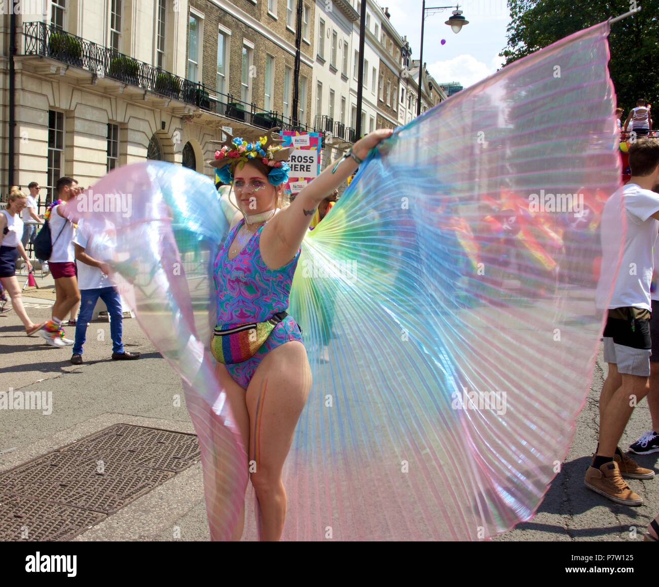 London, UK. 7th July 2018. A woman in a swimming costume and a rainbow coloured sheer cape at Pride in London 2018 Parade, joining more than 1 million attending the march today to celebrate LGBT+. Credit: Dimple Patel/Alamy Live News Stock Photo