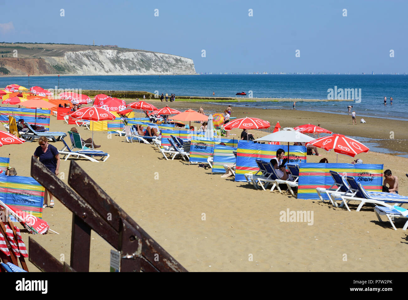 Culver Down, UK. 07th July, 2018. Sunbathers relax and cool off on the beach during the UK's hottest day of the year so far, as the heat wave continues and temperatures reach 33 degrees centigrade. Yachts from the Isle of Wight 'Round the Island Yacht Race' can be seen in the distance. Sandown, UK, Credit: Matthew Blythe/Alamy Live News Stock Photo