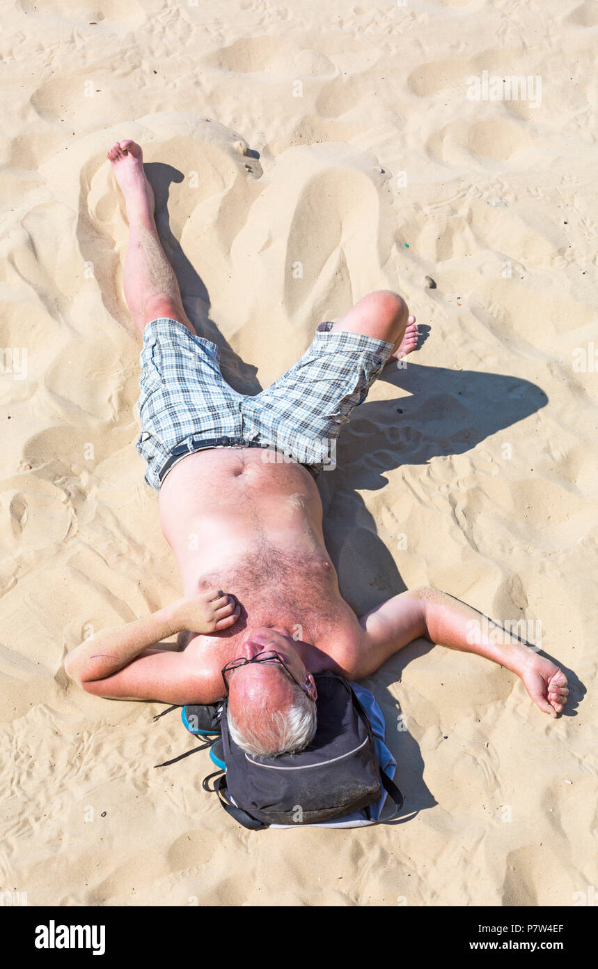 Bournemouth, Dorset, UK. 8th July 2018. UK weather: another hot sunny day as the heatwave continues and thousands of sunseekers head to the  seaside to enjoy the sandy beaches at Bournemouth on the South Coast. Man sunbathing on the beach - looking down on from above. Credit: Carolyn Jenkins/Alamy Live News Stock Photo