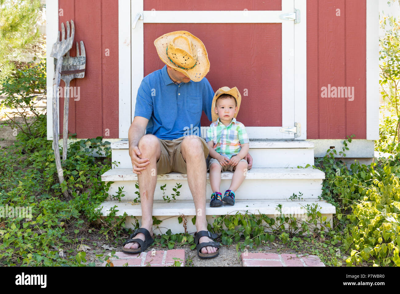 Playful Young Caucasian Father and Mixed Race Chinese Son Wearing Cowboy Hats Stock Photo