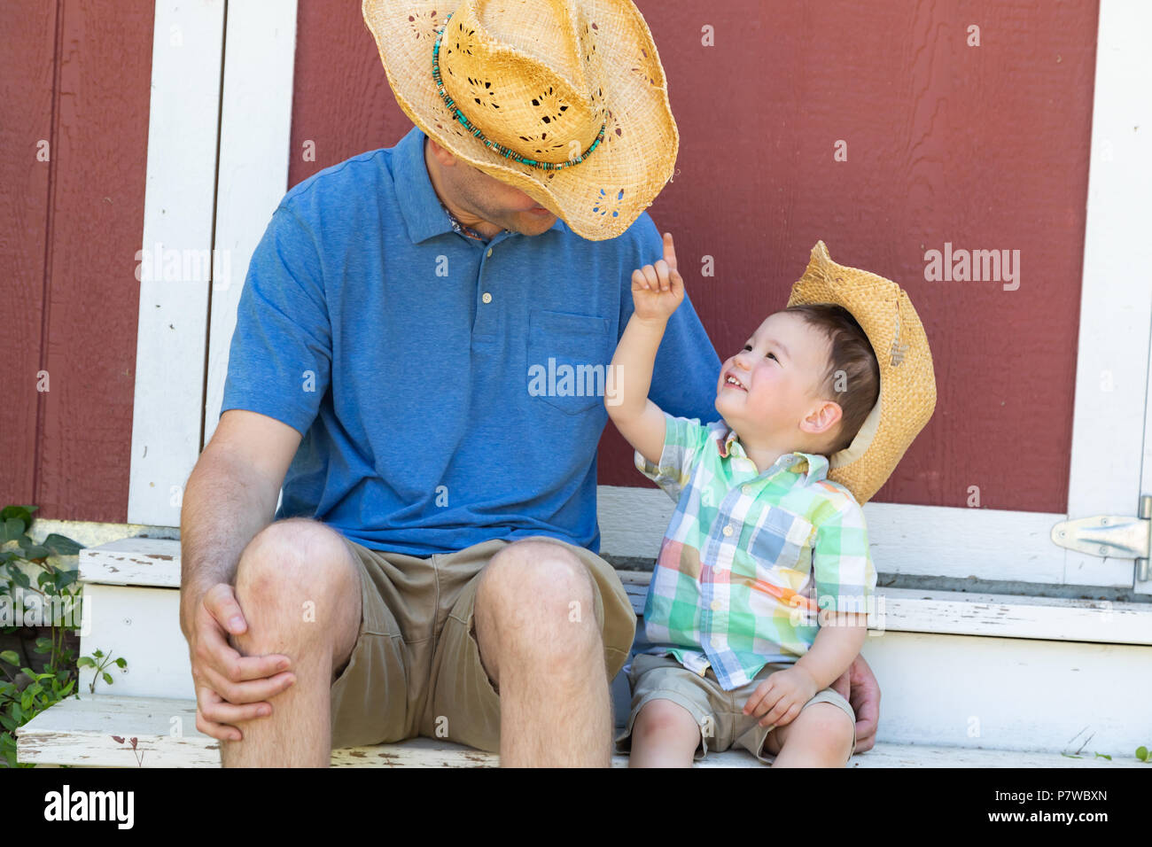 Playful Young Caucasian Father and Mixed Race Chinese Son Wearing Cowboy Hats Stock Photo