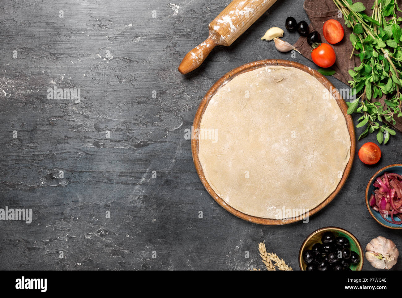 Raw pizza dough with ingredients for cooking vegetarian pizza on the