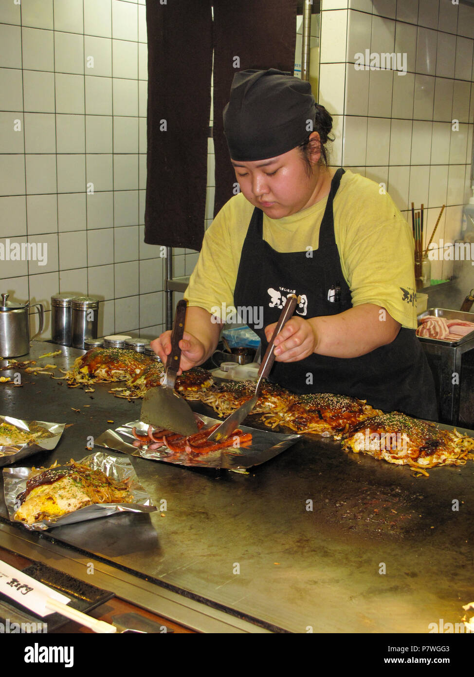 Restaurant kitchen, staff cooking Okonomiyaki savoury pancakes Stock Photo