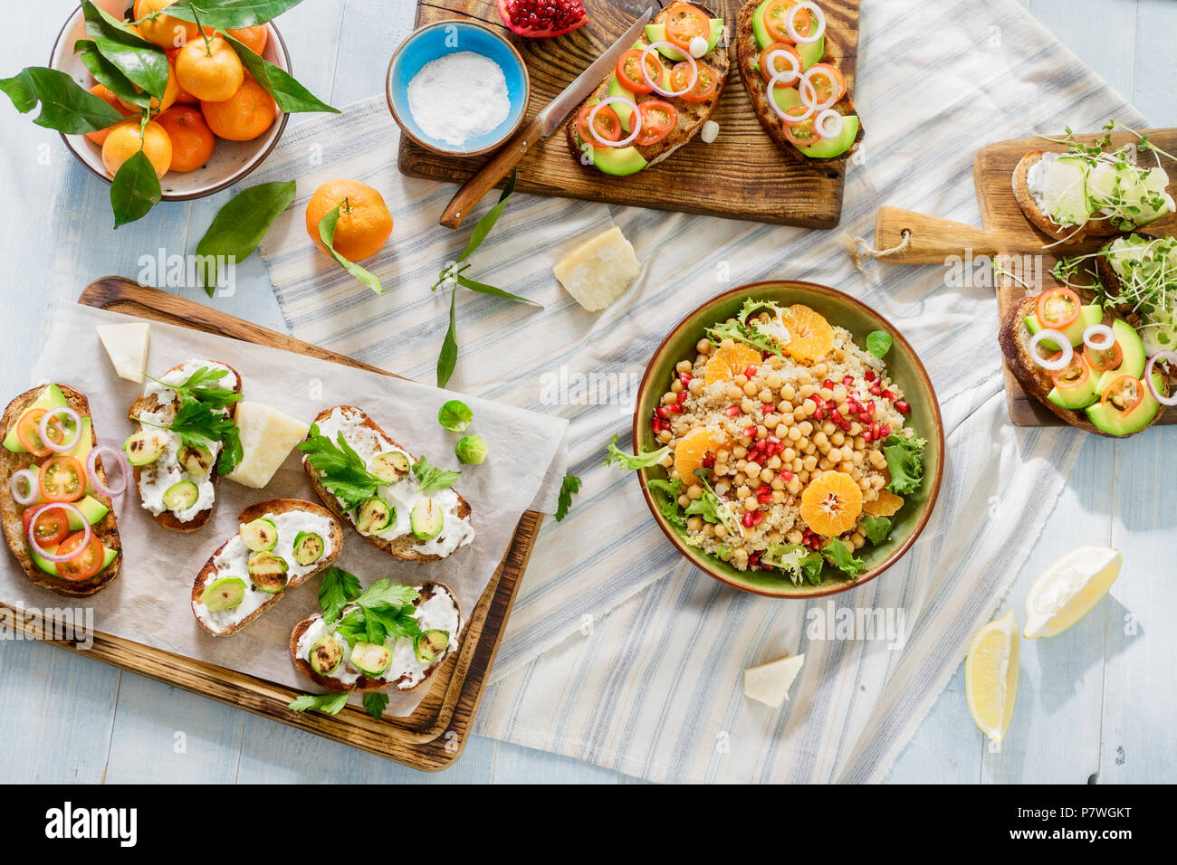 Set of vegetarian dishes on blue wooden table. Bruschetta with tomatoes, cucumbers, Brussels sprouts and salad with chickpeas and quinoa on blue woode Stock Photo