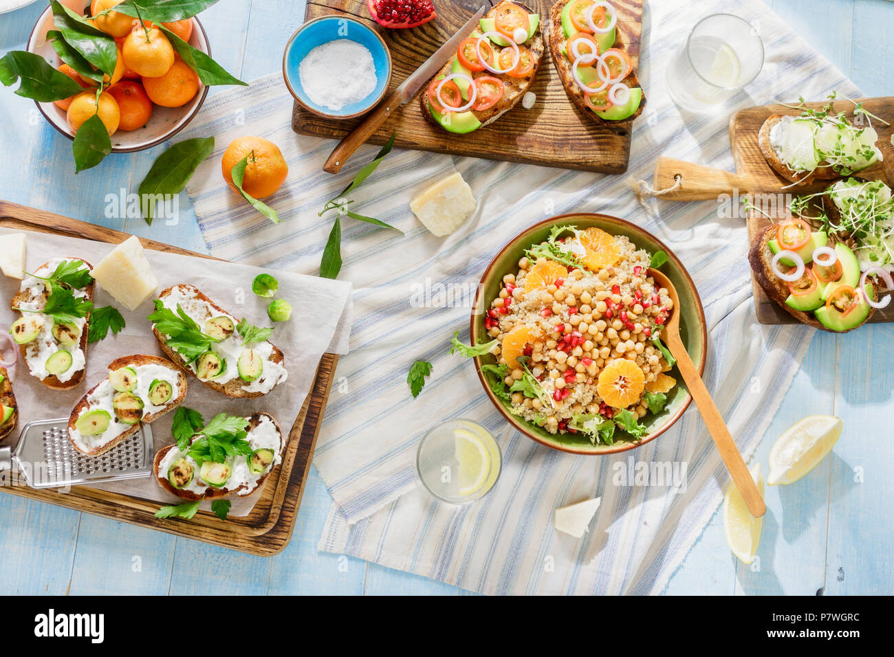 Bruschetta with tomatoes, cucumbers, Brussels sprouts and salad with chickpeas and quinoa on blue wooden table, top view. Tasty and healthy food. Set  Stock Photo