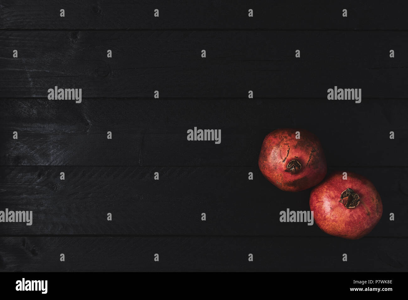 Flat lay of ripe pomegranate fruit on black wooden vintage background. Top view with copy space. Stock Photo