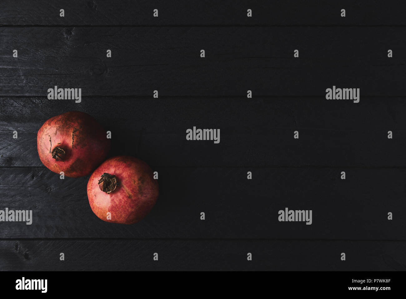 Flat lay of ripe pomegranate fruit on black wooden vintage background. Top view with copy space. Stock Photo
