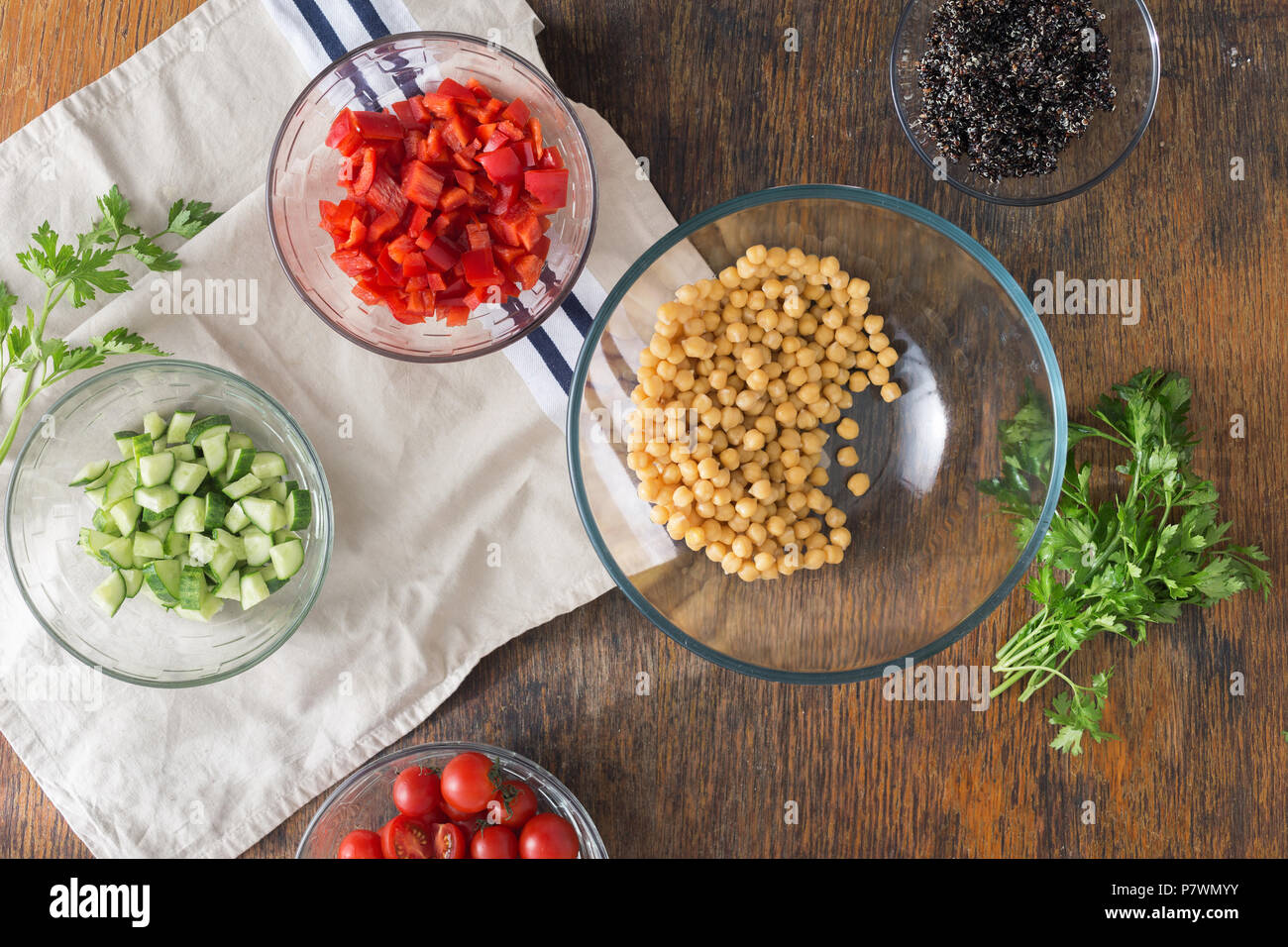 Ingredients for cooking vegetarian healthy salad. Black quinoa, chickpeas, peppers, cucumber, tomatoes and parsley on a wooden table top view Stock Photo