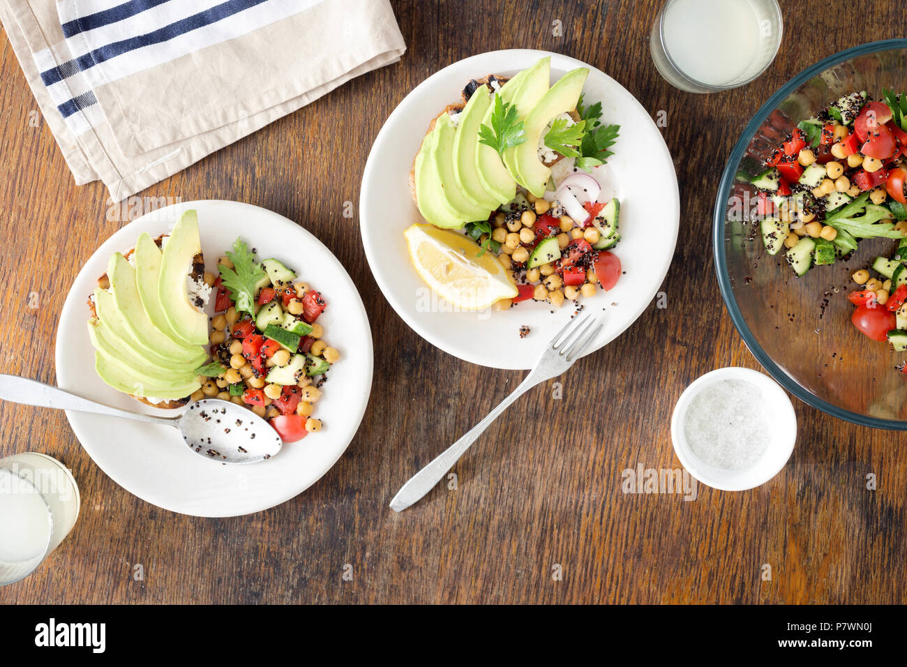 Tasty and healthy vegetarian food. Salad of black quinoa, chickpeas and vegetables with avocado bruschetta on a wooden table with lemonade, top view Stock Photo