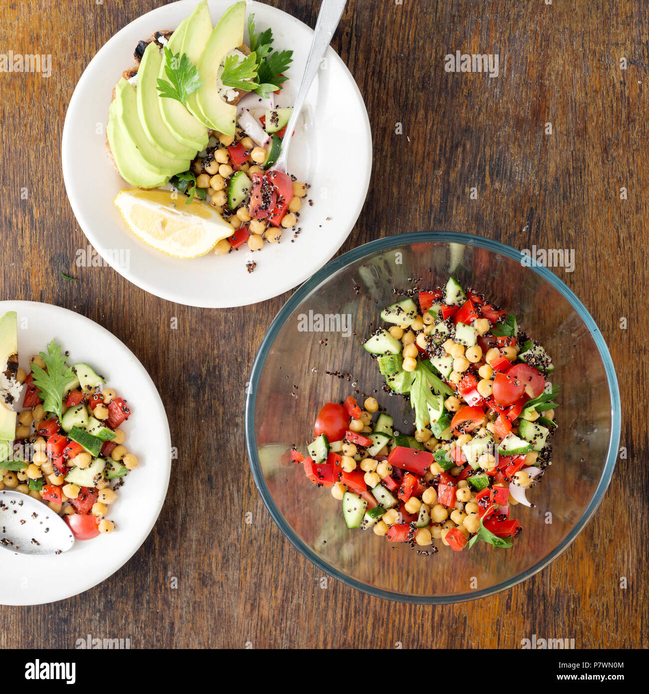 Tasty and healthy vegetarian food. Salad of black quinoa, chickpeas and vegetables with avocado bruschetta on wooden table, top view Stock Photo