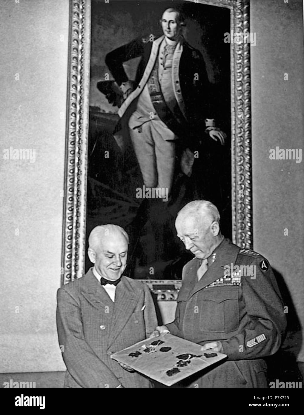 English: Gen. George S. Patton Jr., right, presenting Huntington trustee Robert Millikan with an original 1935 typescript of the Nuremberg Laws signed by Adolf Hitler, on June 11, 1945. During the final days of World War II, as American soldiers were returning home from Germany with helmets, swastika-inscribed flags and other Nazi memorabilia, Gen. George Patton was packing up his own sourvenirs, including four pages of these documents signed by Adolf Hitler that set up the legal framework for the Nazis to kill six million Jews . 11 June 1945 169 Gen. George S. Patton presented the Nuremberg L Stock Photo
