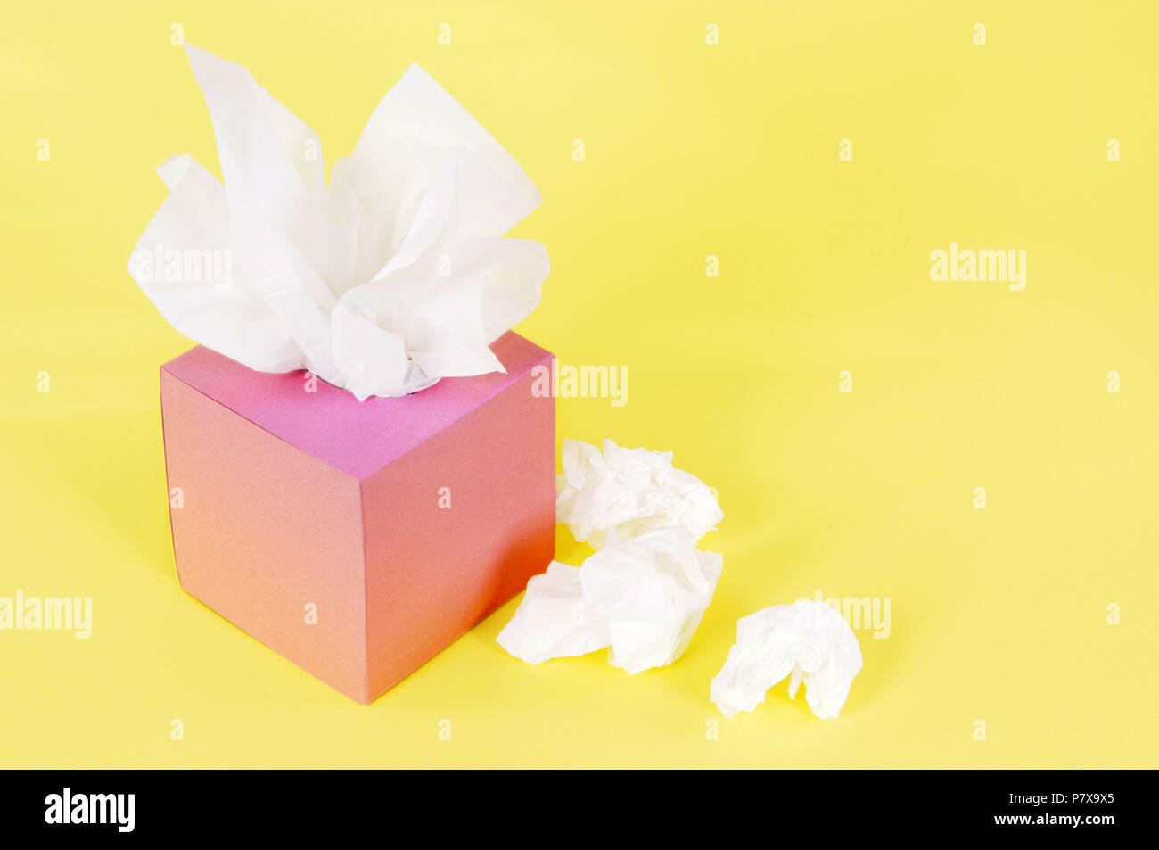 Paper tissues in blank pink box on a yellow background. Stock Photo