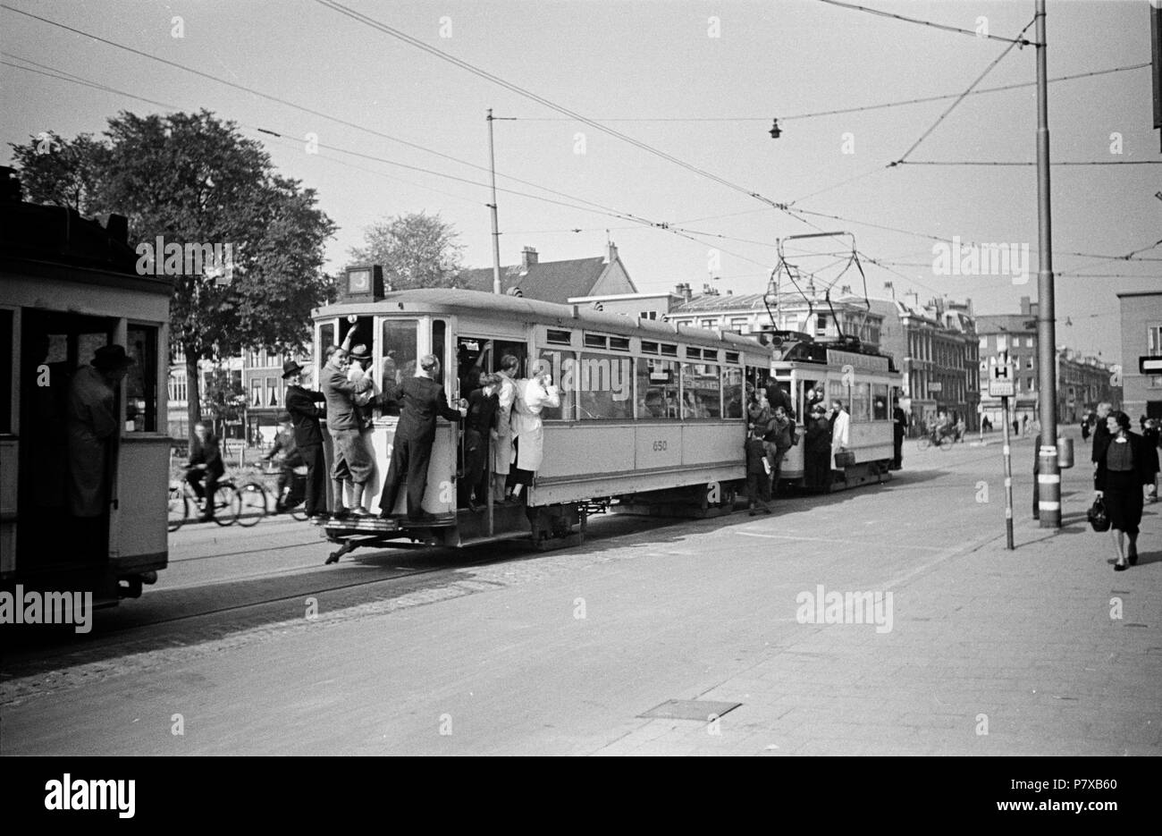 Gemeenten woensdag lip Huizinga collectie overvolle tram - NIOD - 216738. Nederlands: Foto uit de  collectie Huizinga van het NIOD. Een overvolle tram met buiten hangende  passagiers rijdt door de straten van Den Haag.