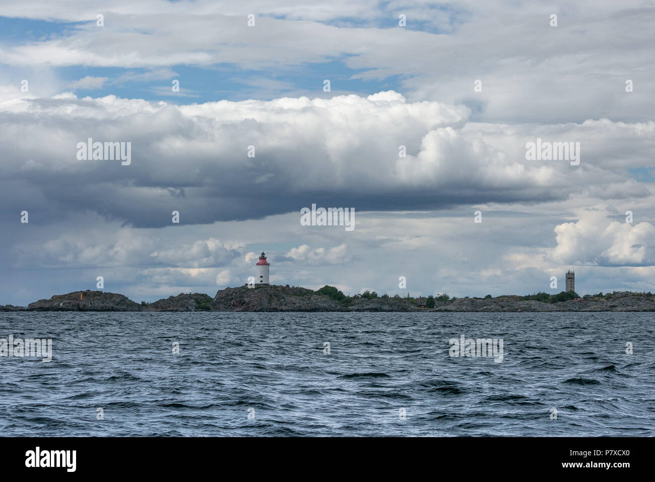A lighthouse in the sea with dramatic sky. Stock Photo