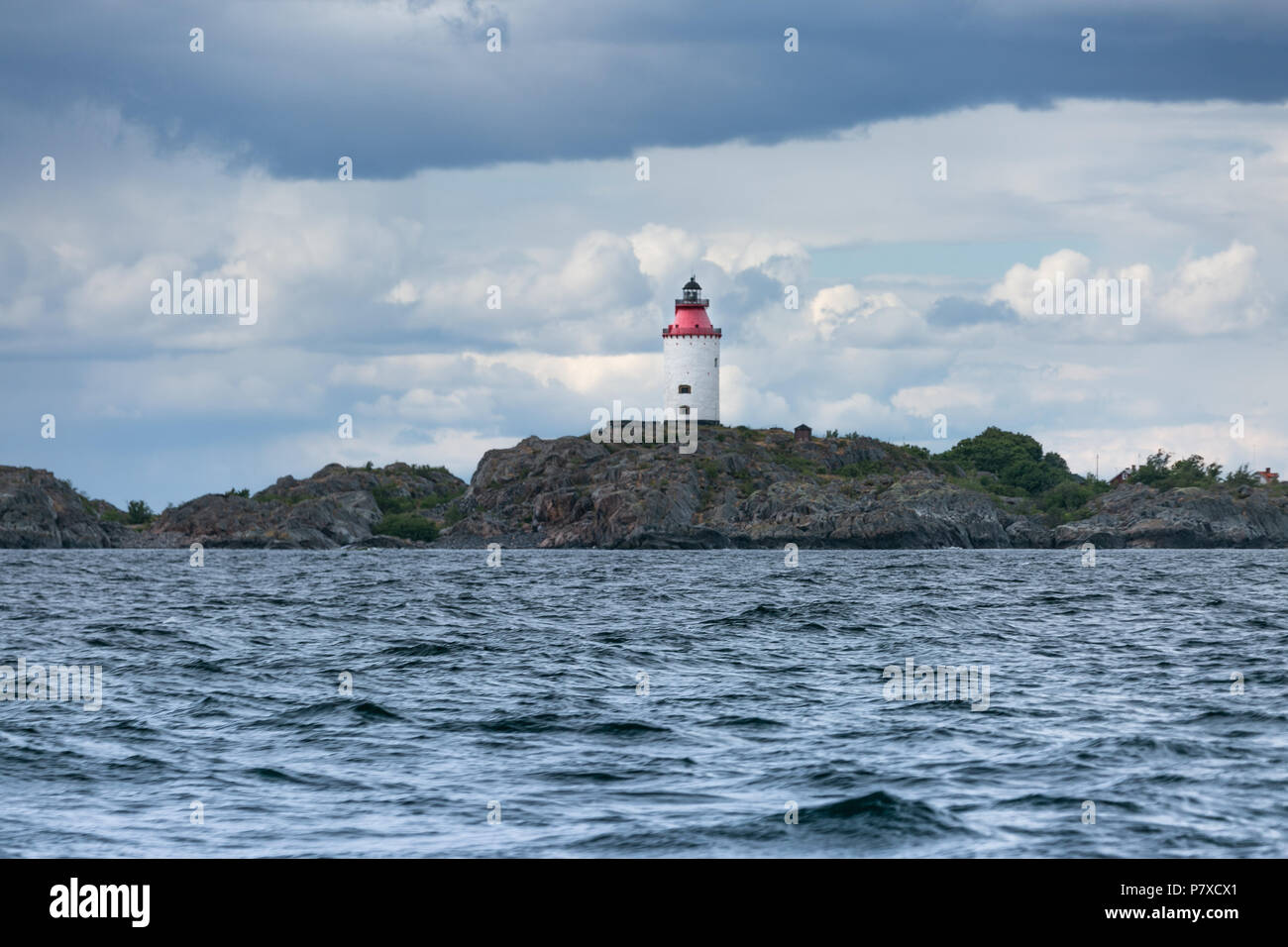 A lighthouse in the sea with dramatic sky. Stock Photo