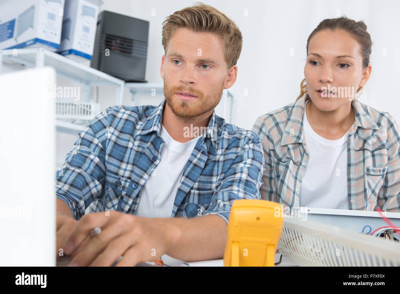 male and female technicians working using multimeter on appliance Stock Photo