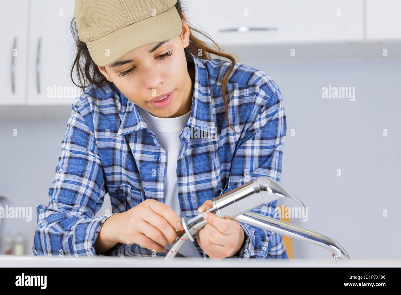 female plumber working on sink using wrench Stock Photo