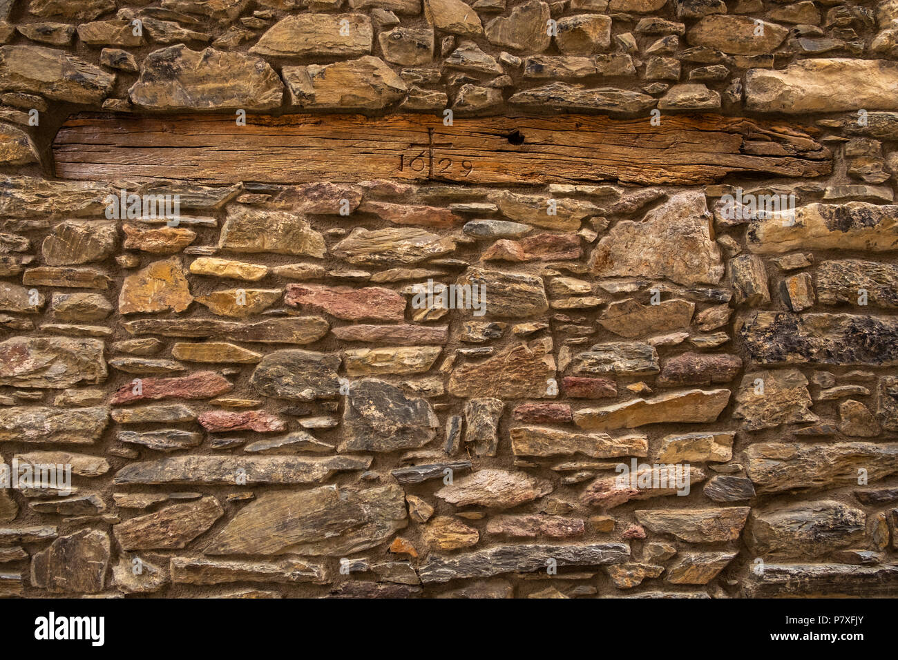 Dated wooden beam set into granite stone wall in Pardines in the Pyrenees, Catalonia, Spain Stock Photo