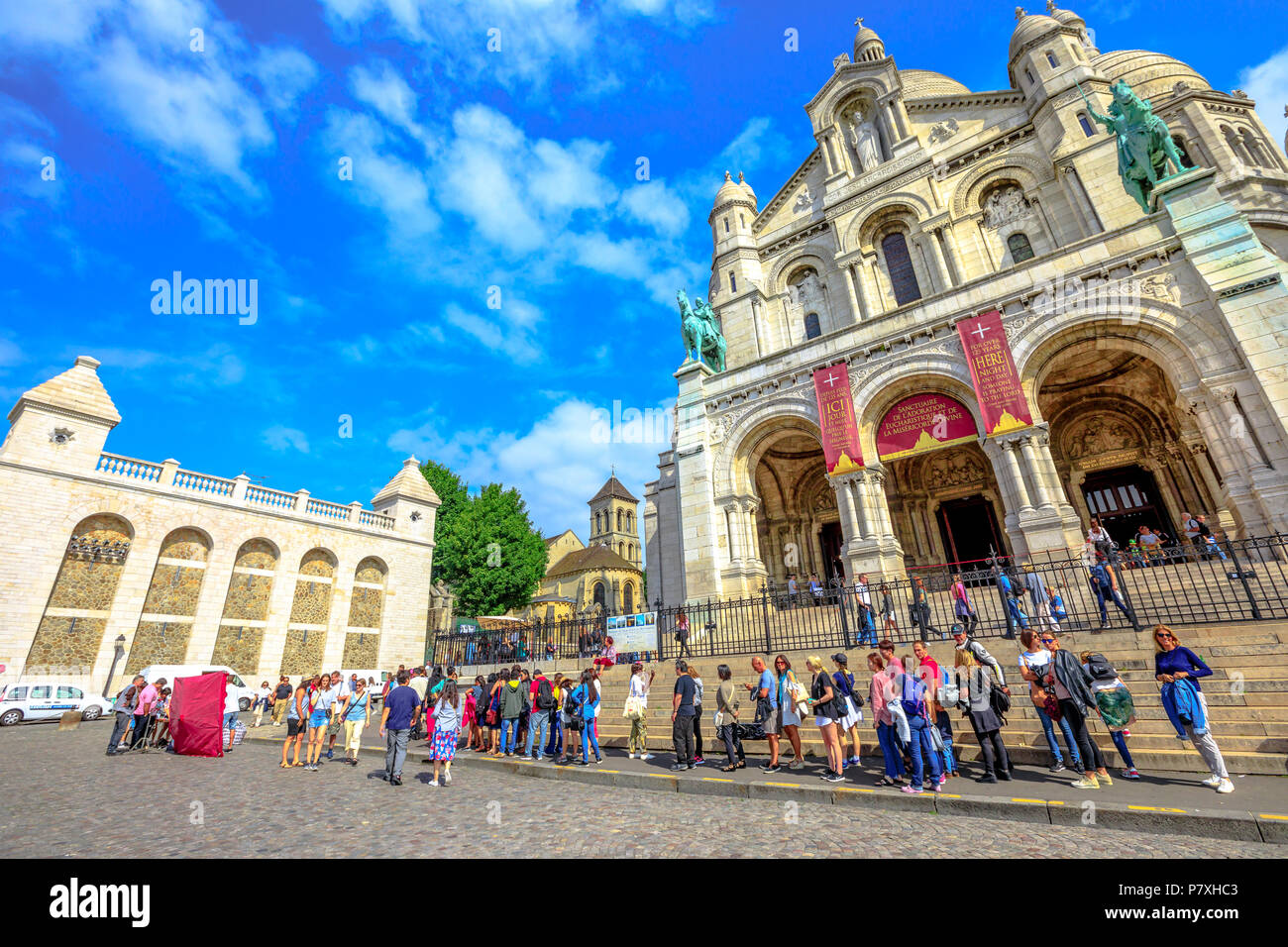 Paris, France - July 3, 2017: perspective view of people in front of Basilique du Sacre Coeur de Montmartre. Sacred Heart Church is a popular attraction and landmark in Paris. Sunny day blue sky. Stock Photo
