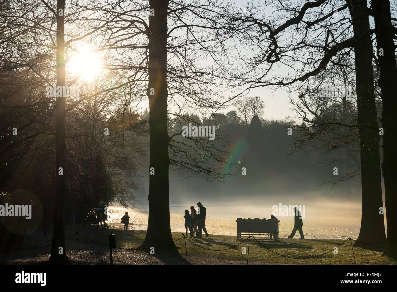 People take a walk in the winter sun around the lake at Claremont National Trust Property Stock Photo