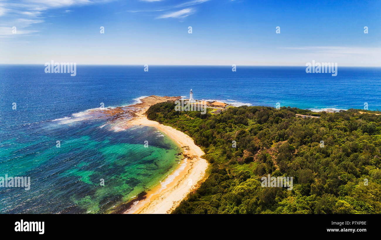 Evergreen gumtree woods in Norah Head reserver around tipping point of sandstone head with Norah lighthouse facing endless Pacific ocean between bays  Stock Photo
