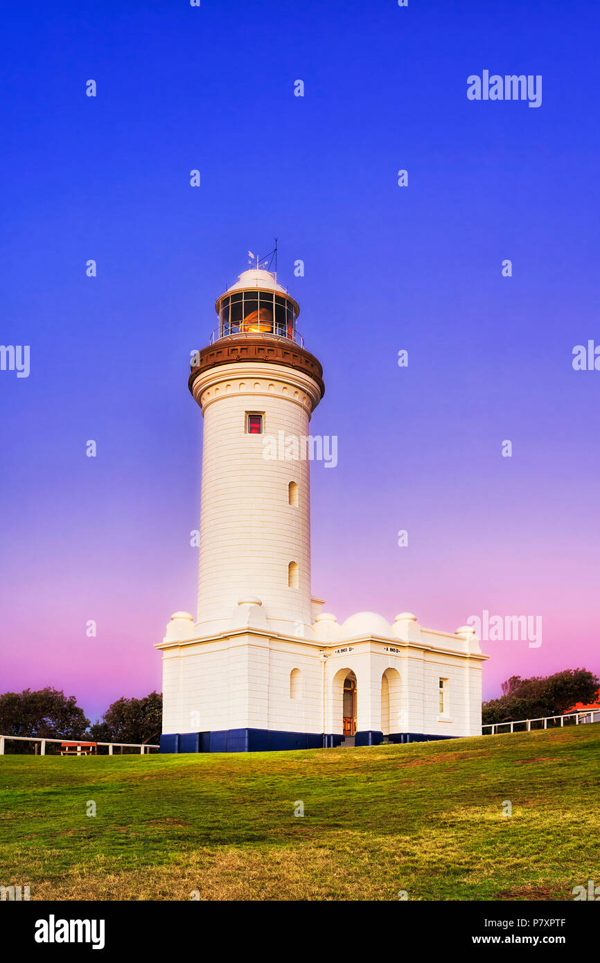 Pink blue sunrise over Norah Head lighthouse on Australian Central coast - top of the hill with green grass around historic landmark building. Stock Photo