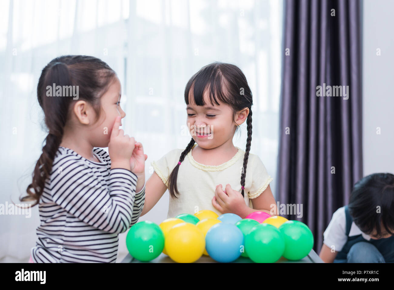 Two little girls and boy playing small toy balls in home together. Education and Happiness lifestyle concept. Funny learning and Children development  Stock Photo