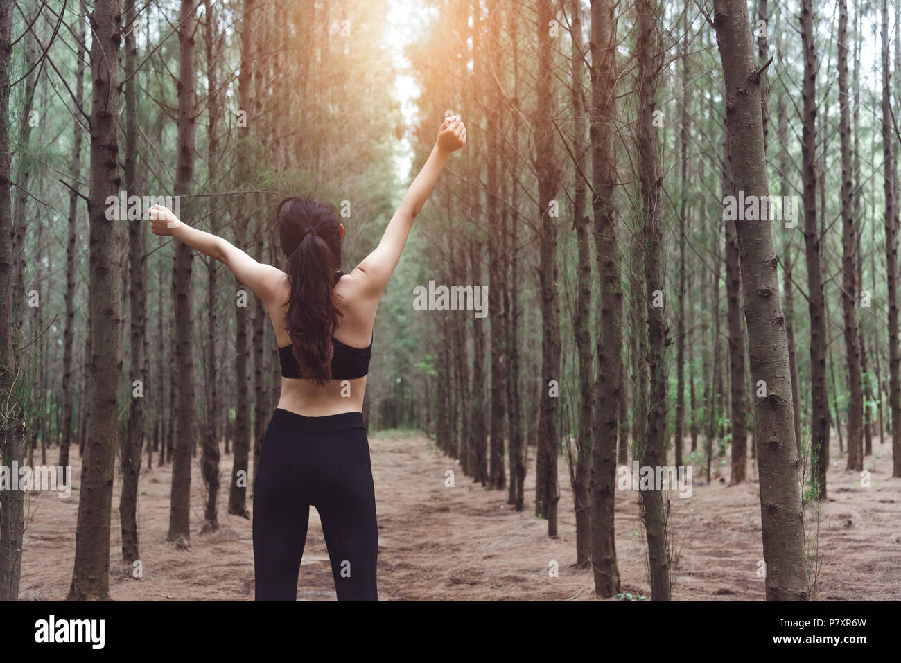 Woman stretching arms and breathing fresh air in middle of pinewood Woman stretching arms and breathing fresh air in middle of pinewood