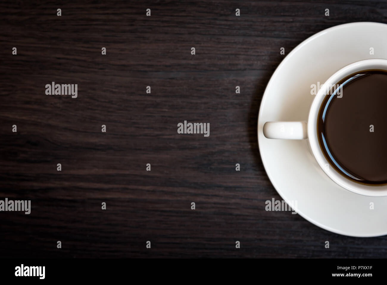 White coffee cup on wood table background with copy space, Half cup with full of coffee, Dark tone still life and vignette, Top view for advertisement Stock Photo