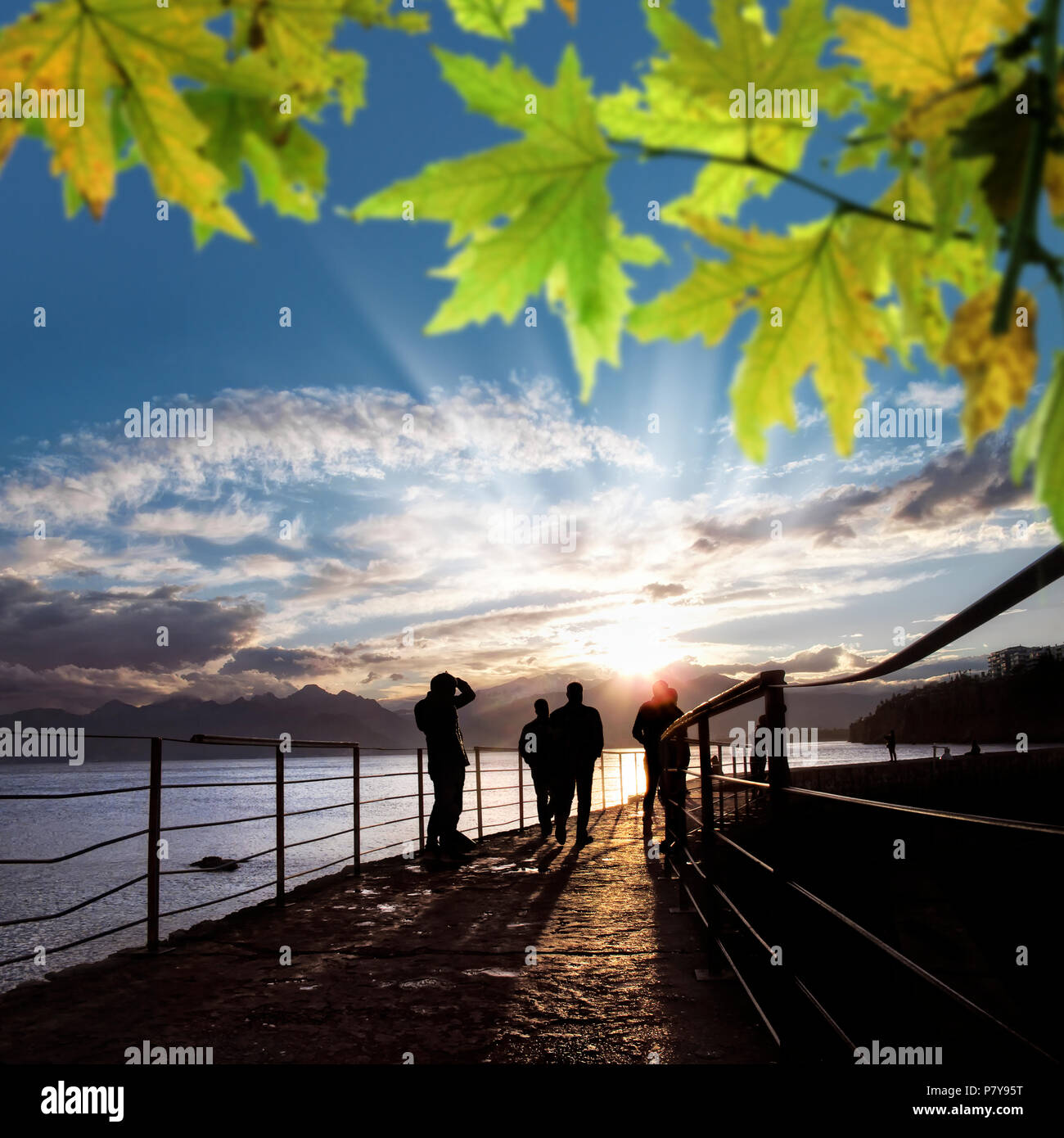 silhouetted people walking on street over sunset sky with sunbeam Stock ...