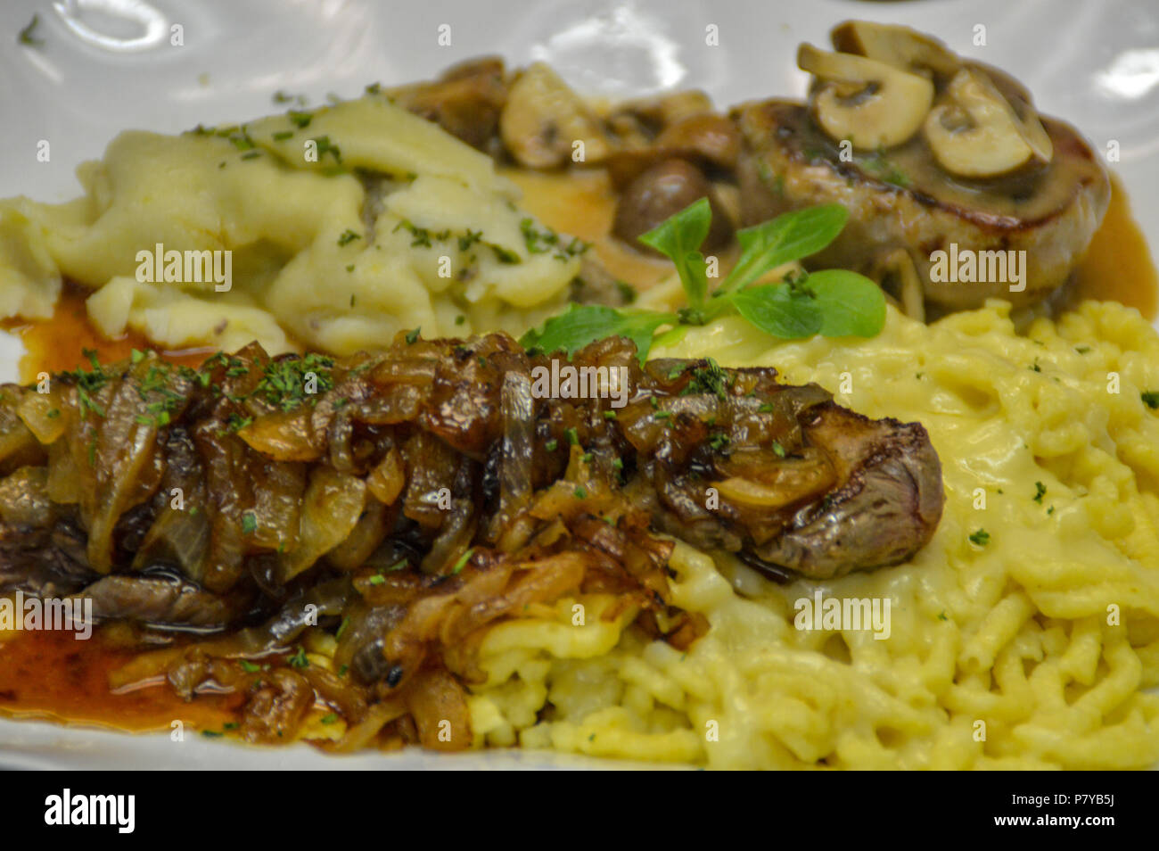 German food. Spätzle, beef steak and pork medallion with saukraut Stock Photo Alamy