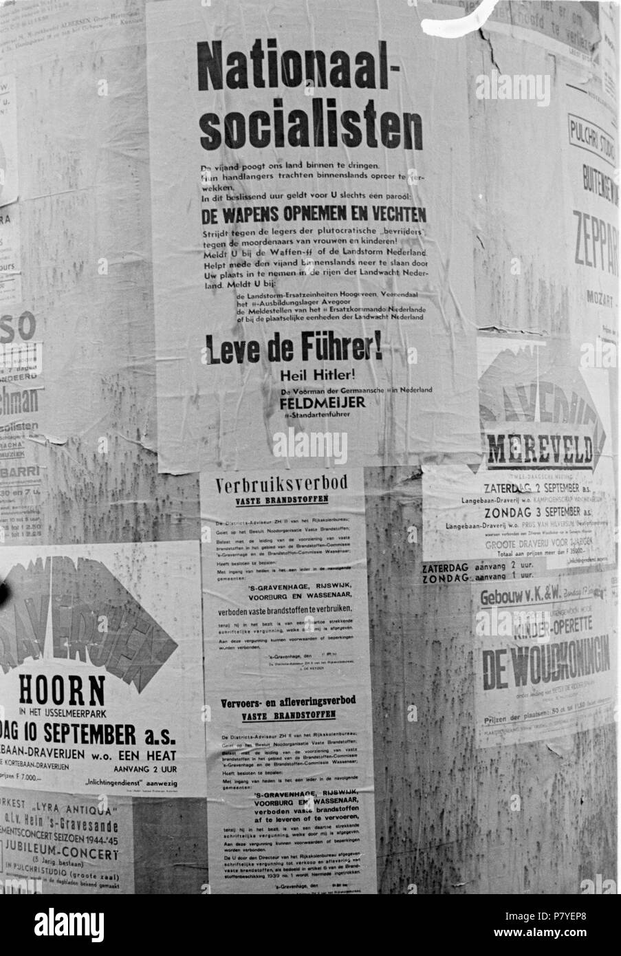 . Huizinga collectie reclamezuil - NIOD - 216368. Nederlands: Foto uit de collectie Huizinga van het NIOD. Op een reclamezuil hangt een affiche met een oproep aan nationaal-socialisten om te gaan vechten tegen de geallieerden, Den Haag (1940-1945) Menno Huizinga was onderdeel van de Ondergedoken Camera en maakte illegaal foto’s tijdens de bezetting. Dit deed hij hoofdzakelijk in zijn woonplaats Den Haag. Unknown date 36 BC856 HUI-1059 Stock Photo
