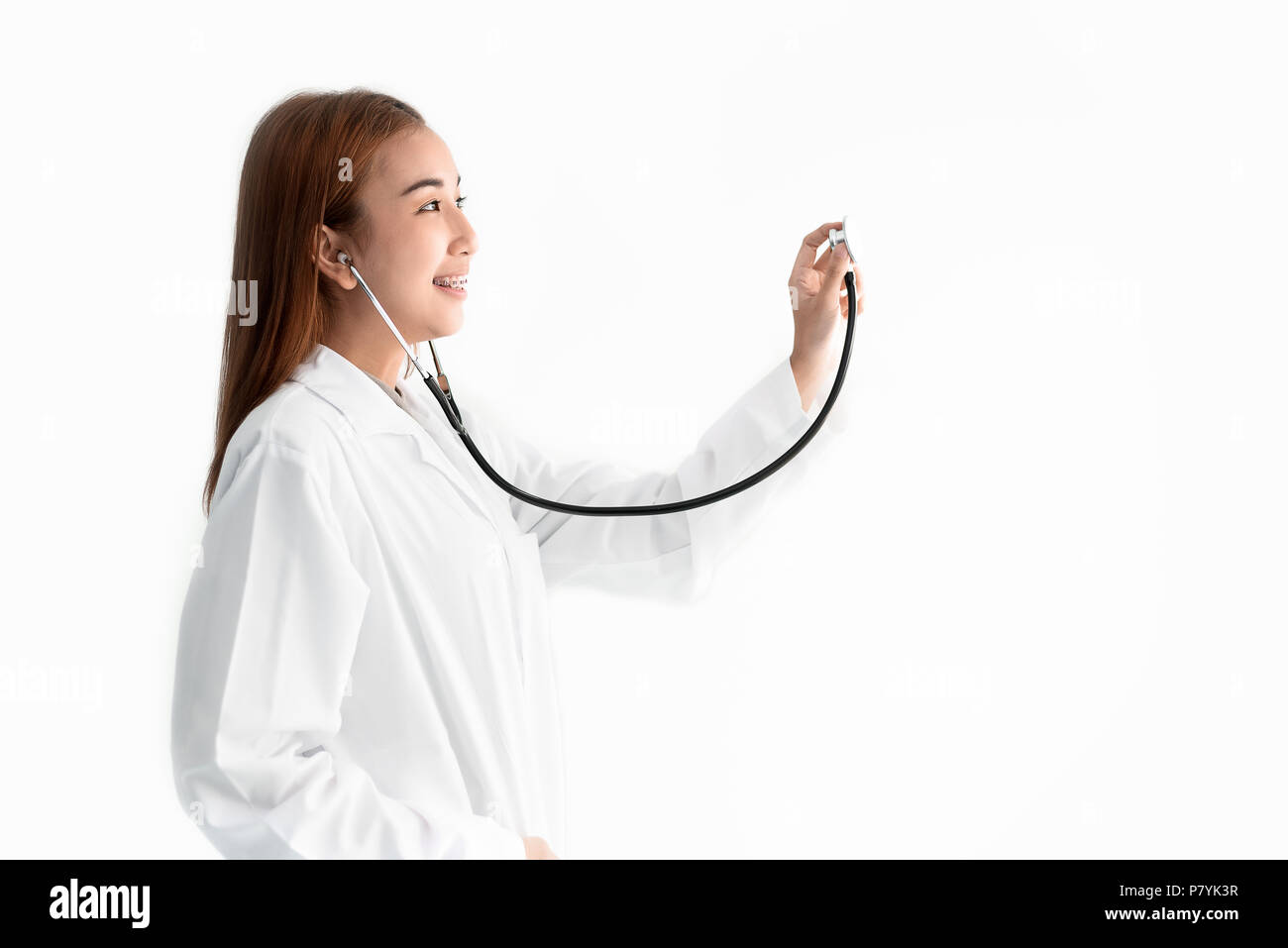 Female doctor is holding stethoscope and hear heart beat sound on white isolated background. Medical and Healthcare concept. Hospital and people theme Stock Photo