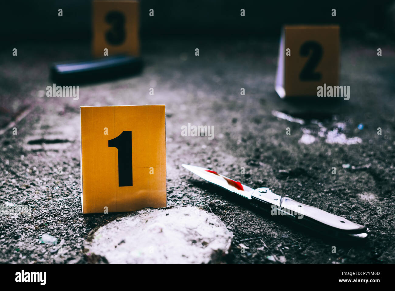 Evidence markers with knife and magazine of gun on the ground. Sign of accident and murder of criminal scene concept.Police and thieve theme Stock Photo