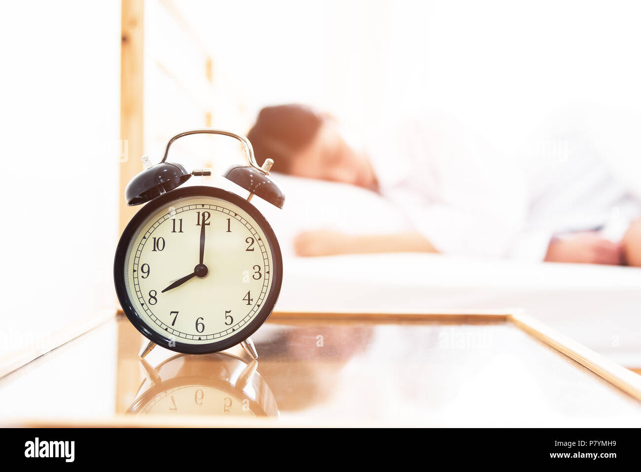 Alarm clock with sleeping woman in bed room. Lazy time in holiday