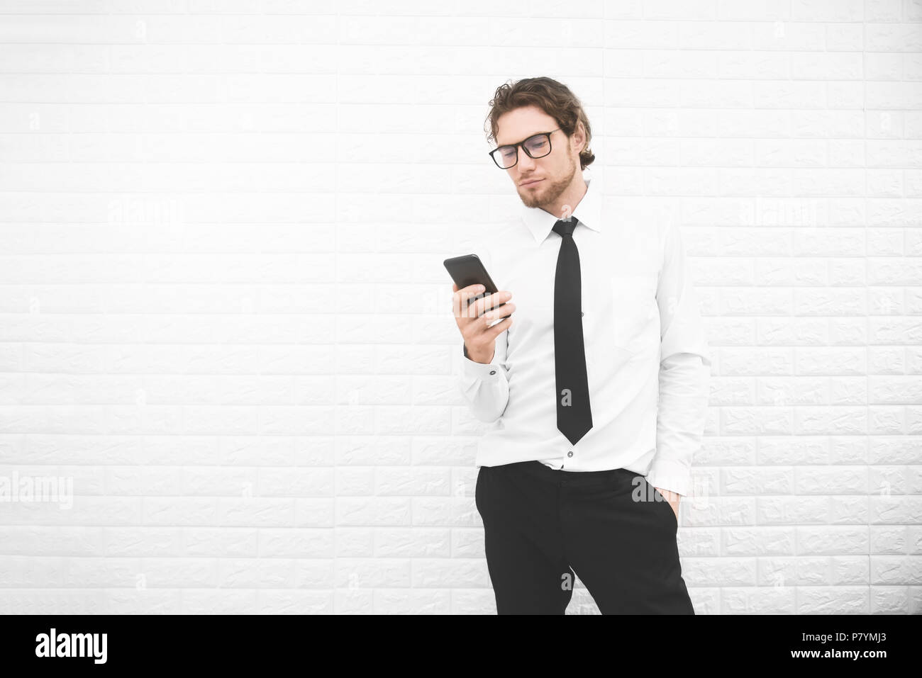 Businessman in formal uniform and using smartphone or mobile phone in front of white wall, Business and fashion concept. Cross processing and Split to Stock Photo