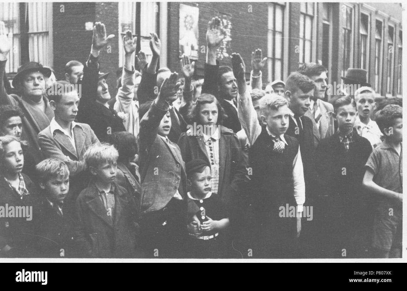 . NSB straatpropaganda. Nederlands: NSB straatpropaganda. 'Kinderen brengen de Hitlergroet. De NSB propaganda deed er alles aan om jongeren te winnen voor de Jeugdstorm.' Deze foto is afkomstig uit het archief van de Fotodienst der NSB. Unknown date 289 NSB straatpropaganda - Fotodienst der NSB - NIOD - 77380 Stock Photo