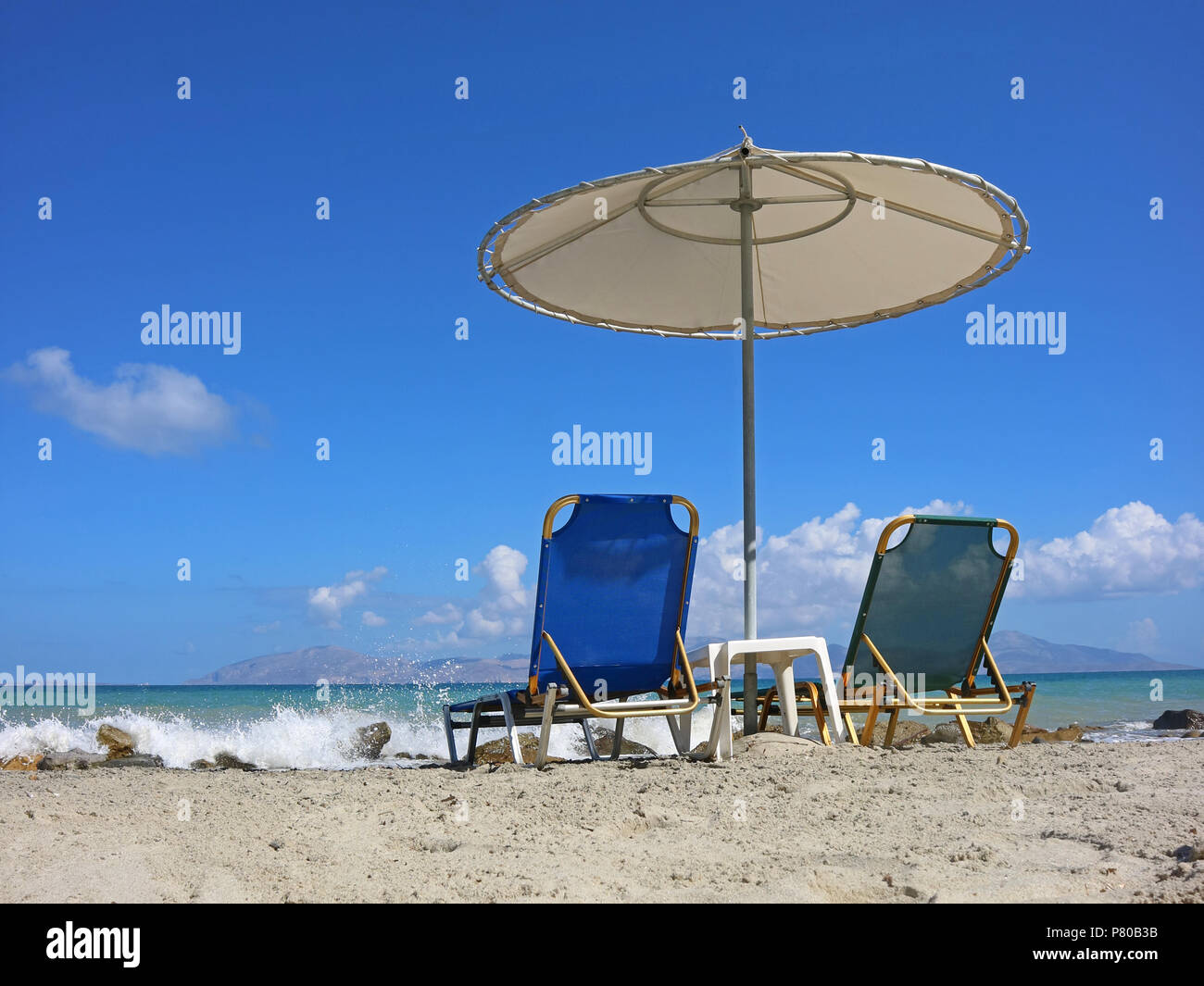 empty sunbeds on the beach with splashing waves Stock Photo