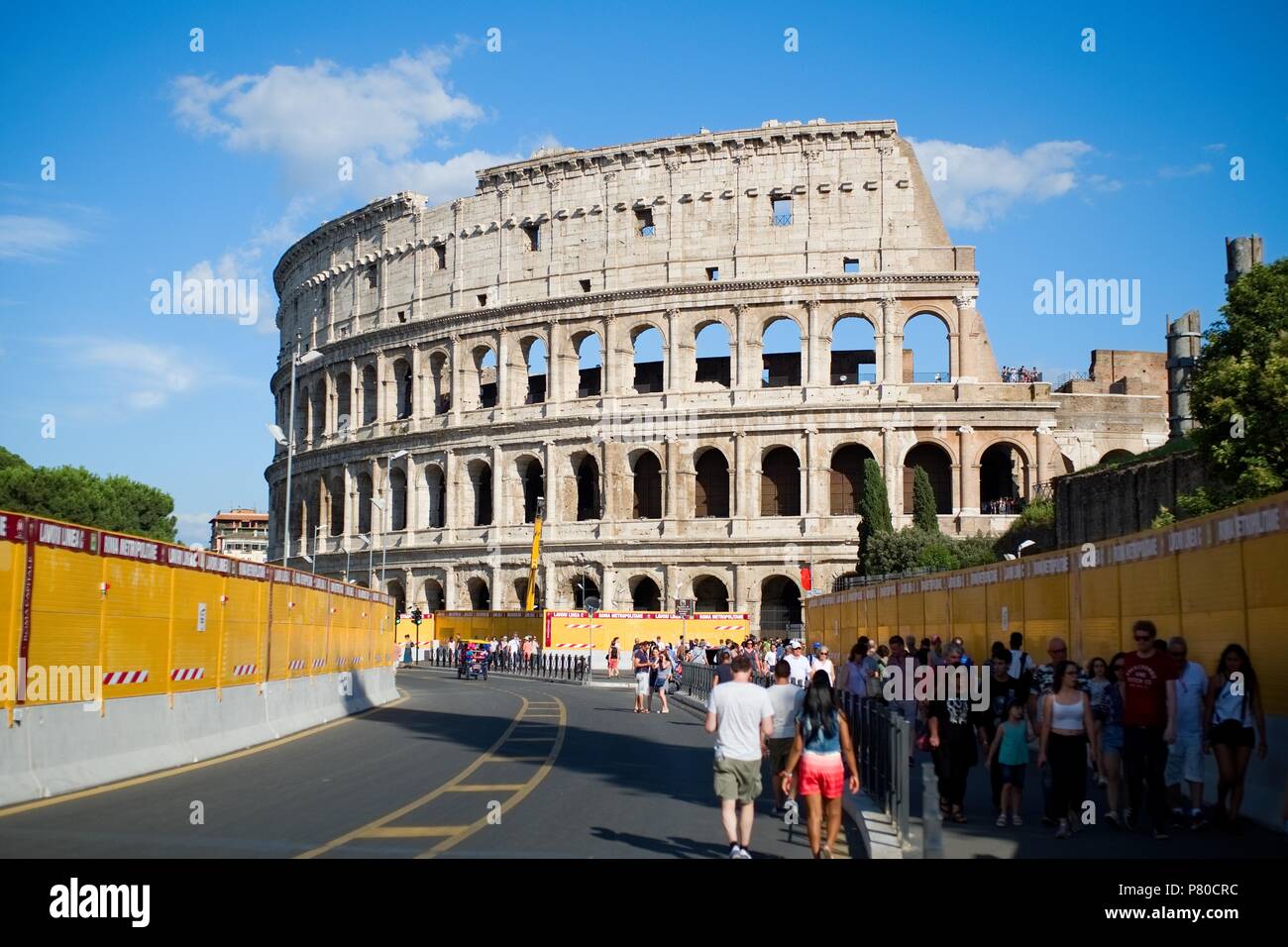 ROME, ITALY - 29 JUNE 2018: View of the Colosseum, with tourists going to visit it, with the barriers that delimit the works for the construction of t Stock Photo