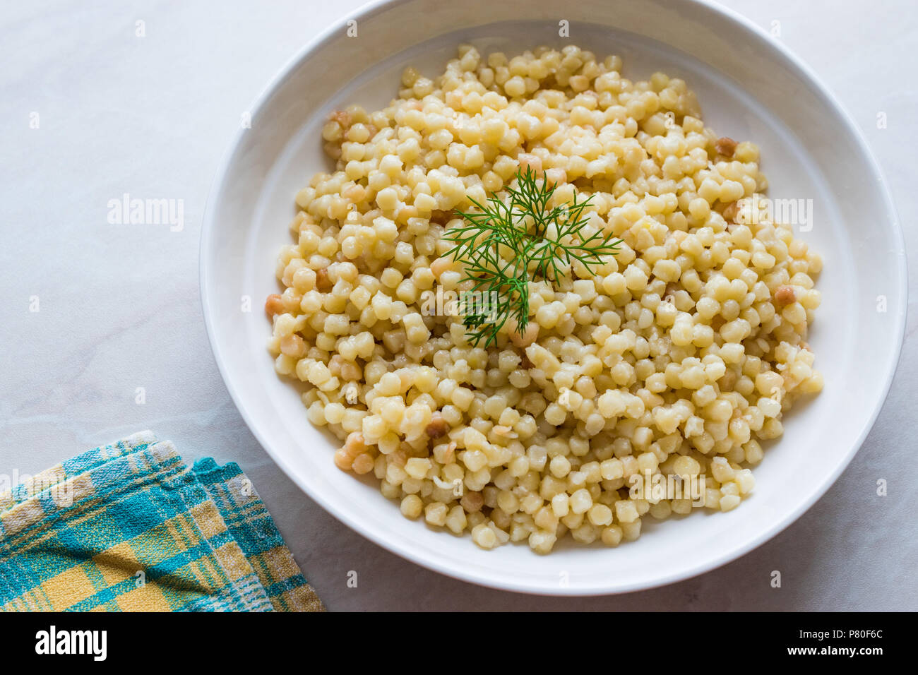 Cooked Couscous with Dill served in White Plate / Turkish Kuskus. Traditional Organic Food. Stock Photo