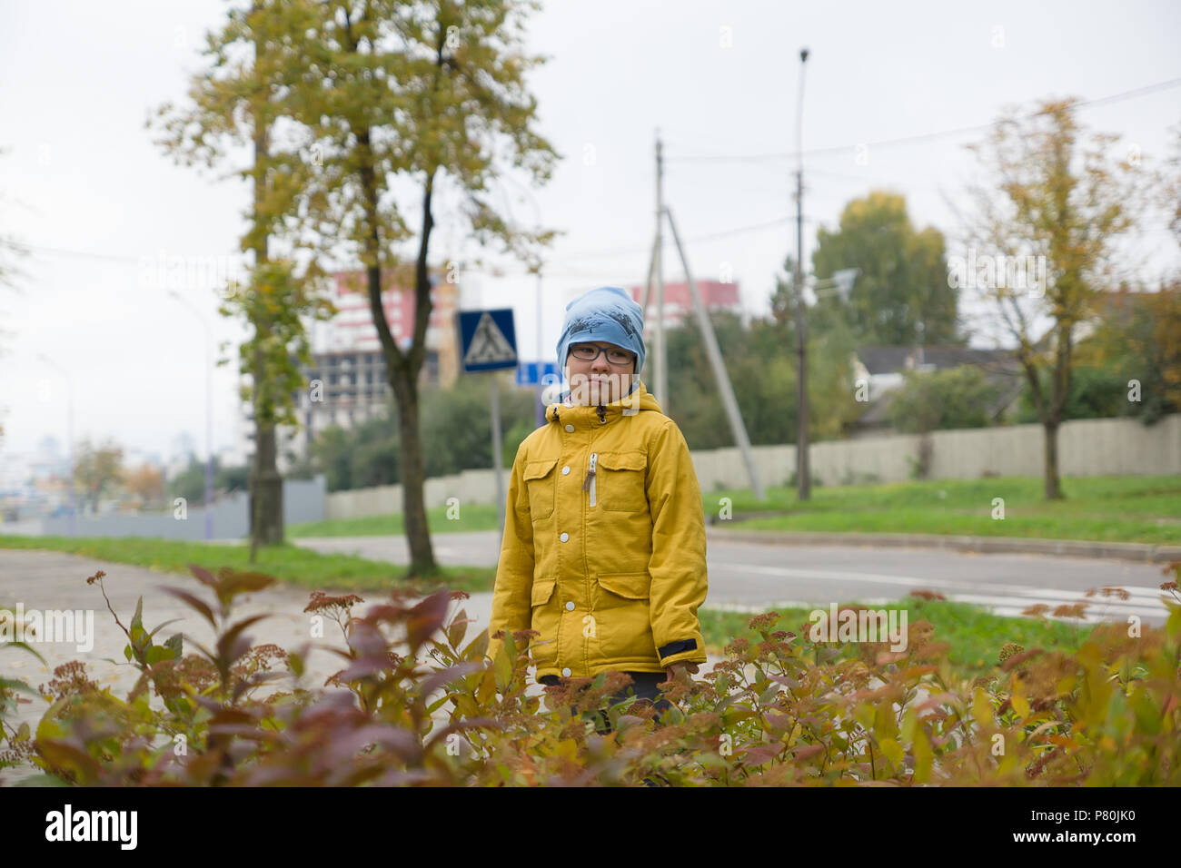 boy in a yellow jacket is resting in an autumn park Stock Photo