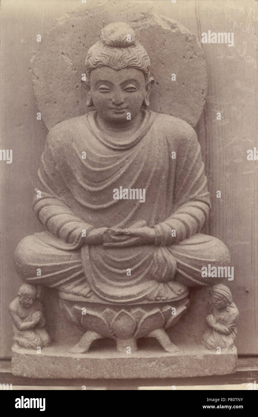 English: Statue of a Buddha seated on a lotus throne, Swat Valley Photograph a statue of Budda sat on a lotus throne taken by Alexander .E Caddy in 1896. The ancient kingdoms of Udyana (Swat) and Gandhara (Peshawar), ruled by the Kushans from the first century AD, corresponded fairly closely with the northern part of the North West Frontier Province. The sculpture of the area, referred to as Gandharan, was influenced by Graeco-Roman elements and this influence can be seen in the draped clothing the figure wears, and in the naturalistic modelling of the body. In 1895 Surgeon-Major L.A.Waddell w Stock Photo