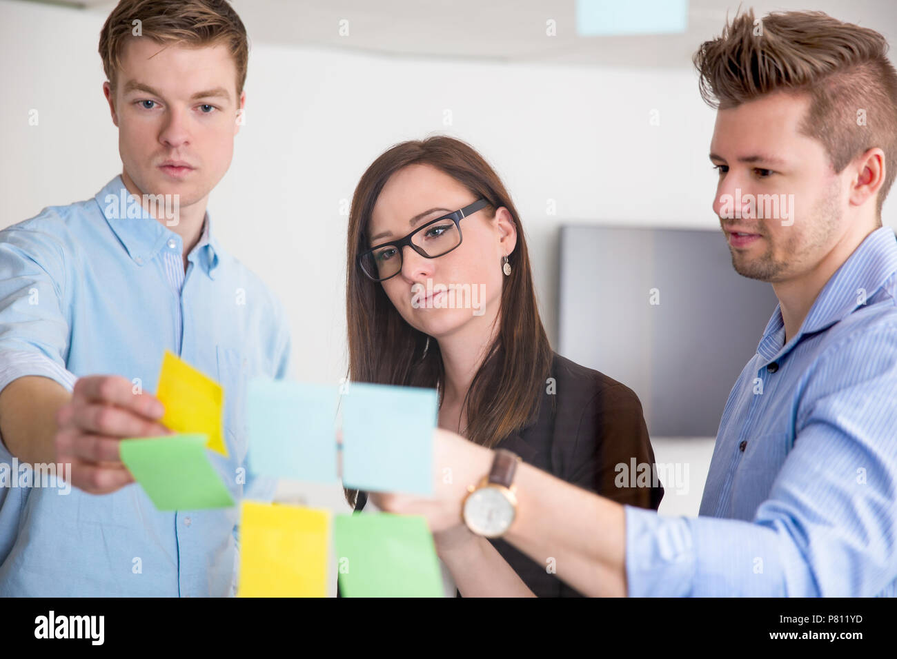 Business Colleagues Discussing Over Adhesive Notes Stuck On Glas Stock Photo