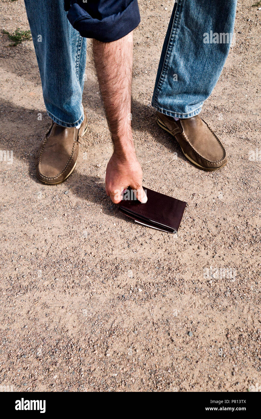 man finding a wallet lost on the ground and picking it up Stock Photo