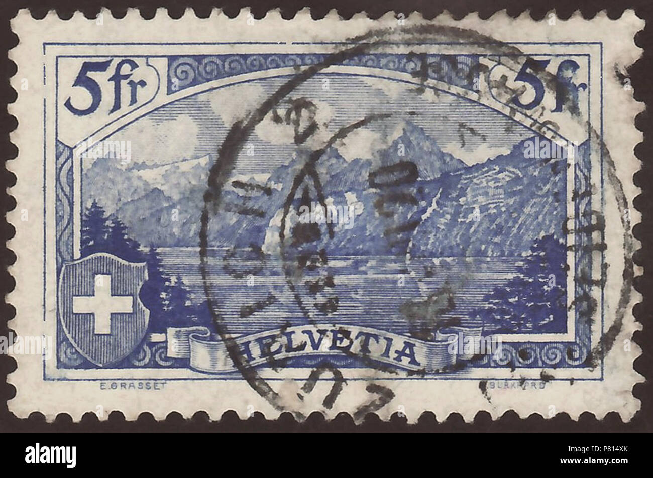 Stamp of Switzerland; 1914; definitive stamp of the issue 'Mountains and Landscapes'; drawing of the 'Rütli' from the 'Vierwaldstätter See' ('Lake Lucerne'); stamp postmarked in Zürich, 1920; special characteristic: engraver name is 'A. Burkhard'; Unfortunately is this stamp damaged. Stamp: Michel: No. 122; Yvert et Tellier: No. 143; AFA: No. 140 Color: ultramarine on white paper with siver strands (filaments) (on the backside recognizable) Watermark: Switzerland No. 2 (multiple Swiss crosses) Nominal value: 5 fr. (Franken, Francs) Postage validity: from July 1914 until 31 December 1942 Stamp  Stock Photo