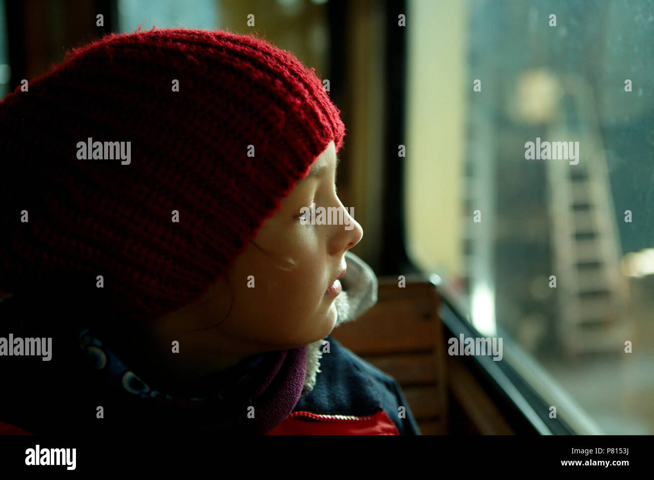 girl in red cap loking at old train window Stock Photo