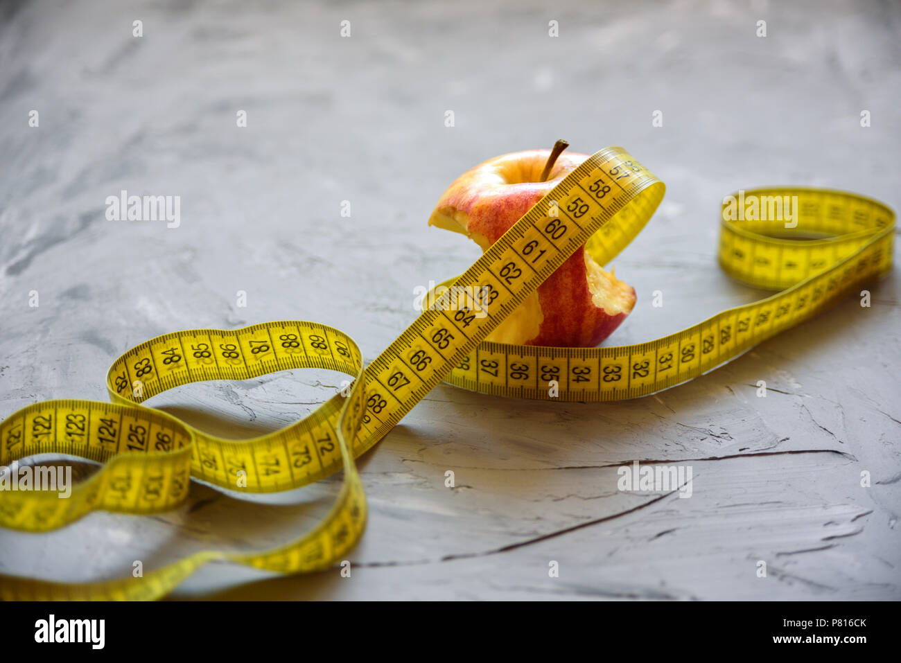 diet, healthy eating, food and weigh loss concept - close up of apple and measuring tape Stock Photo