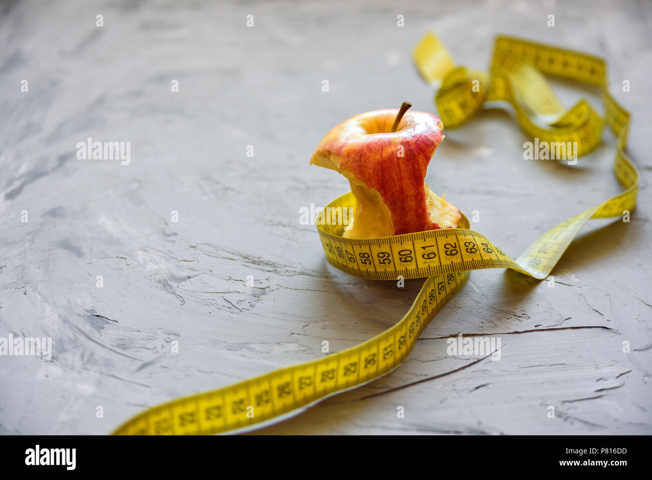 diet, healthy eating, food and weigh loss concept - close up of apple and measuring tape Stock Photo