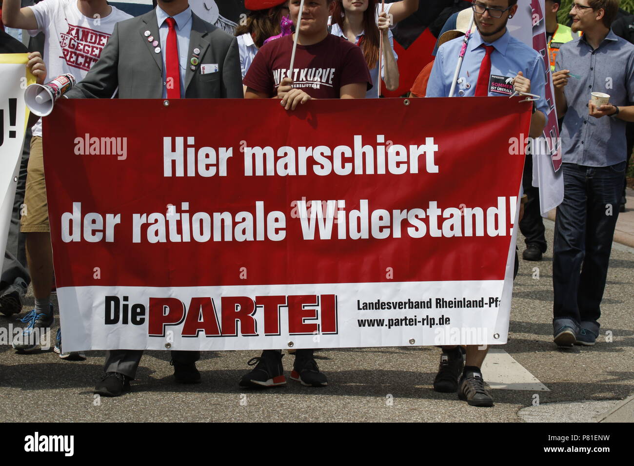 Kandel, Germany. 07th July, 2018. Counter protesters from the party 'Die Partei' carry a banner that reads 'Here marches the rational resistance', a word play on 'National Resistance', the name of a group of far-right organisations in Germany. Around 200 people from right-wing organisations protested for the 10. time in the city of Kandel in Palatinate against refugees, foreigners and the German government. They called for more security of Germans and women from the alleged increased violence by refugees. The place of the protest was chosen because of the 2017 Kandel stabbing attack, in which  Stock Photo