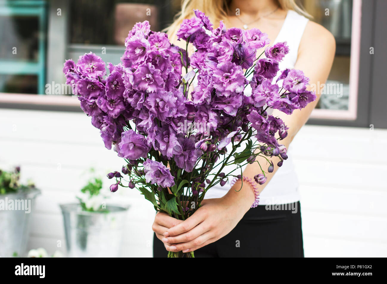 Bouquet of purple lilac delphinium in women's hands on the street Stock Photo